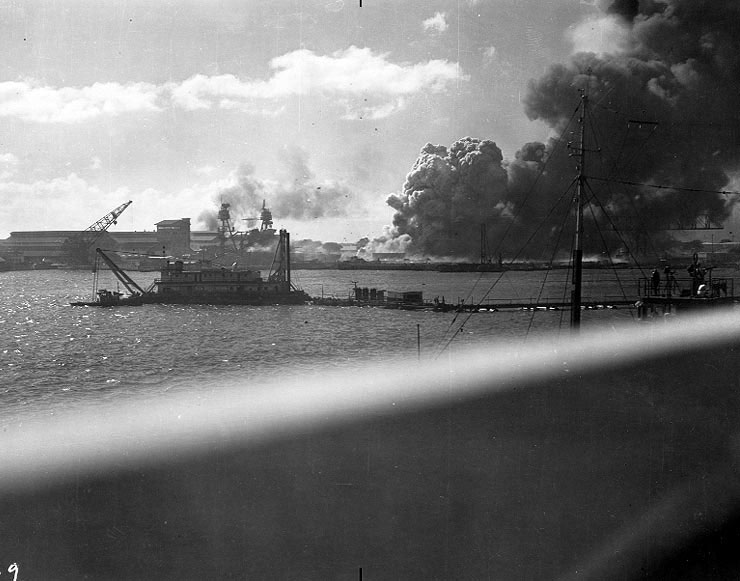 View of Pearl Harbor from Ford Island with the dredge 'Turbine' in the middle of the South Channel, 7 Dec 1941; note Pennsylvania in center of background and Shaw burning at right