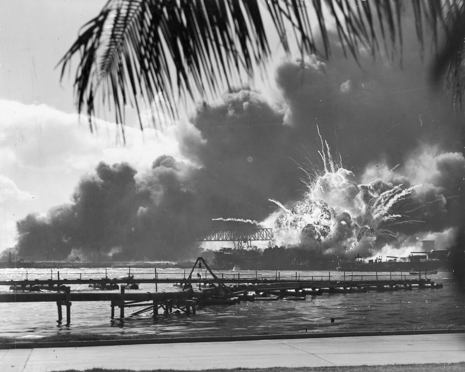 Photo capturing the moment the powder magazine of the USS Shaw exploded during the Pearl Harbor Attack, 7 Dec 1941 at about 0930. Note the after turrets of the USS Nevada passing in the channel at right.