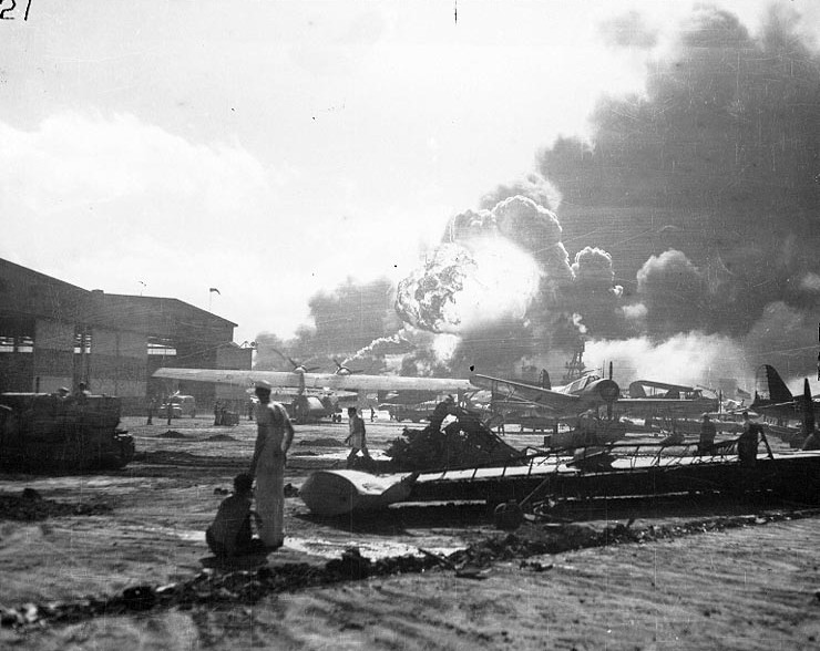 View of Naval Air Station Ford Island, Oahu, US Territory of Hawaii, 7 Dec 1941; note USS Shaw (exploding) and USS Nevada; PBY, OS2U, and SOC aircraft
