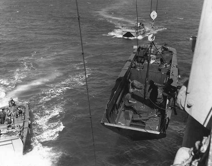 LCVP landing craft suspended from a transport's davits, off the Gela invasion beaches, 10 Jul 1943; note LCM of APA Oberon in background
