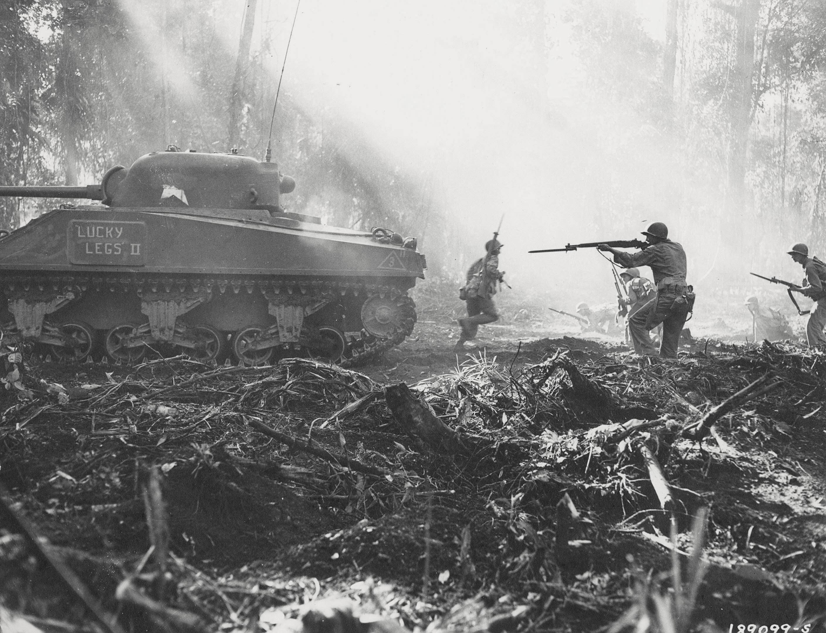 American troops advanced under the cover of M4 Sherman tank 'Lucky Legs II' during mop up operations on Bougainville, Solomon Islands, Mar 1944