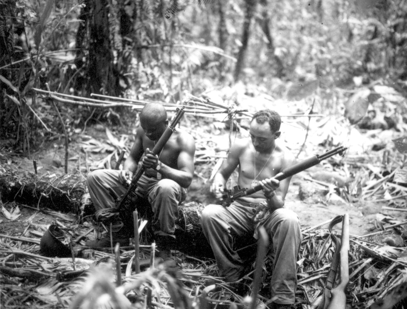 Sergeant John Cark and Staff Sergeant Ford Shaw of E Company, 25th Combat Team, US Army 93rd Division cleaning their rifles alongside the East West Trail, Bougainville, Solomon Islands, 4 Apr 1944