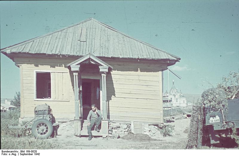 German soldier taking a break at the steps in front of a house, near Stalingrad, Russia, Sep 1942
