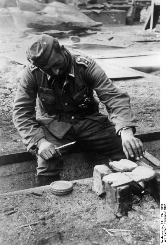 A German Army sergeant roasting bread on a small fire, Stalingrad, Russia, Nov 1942