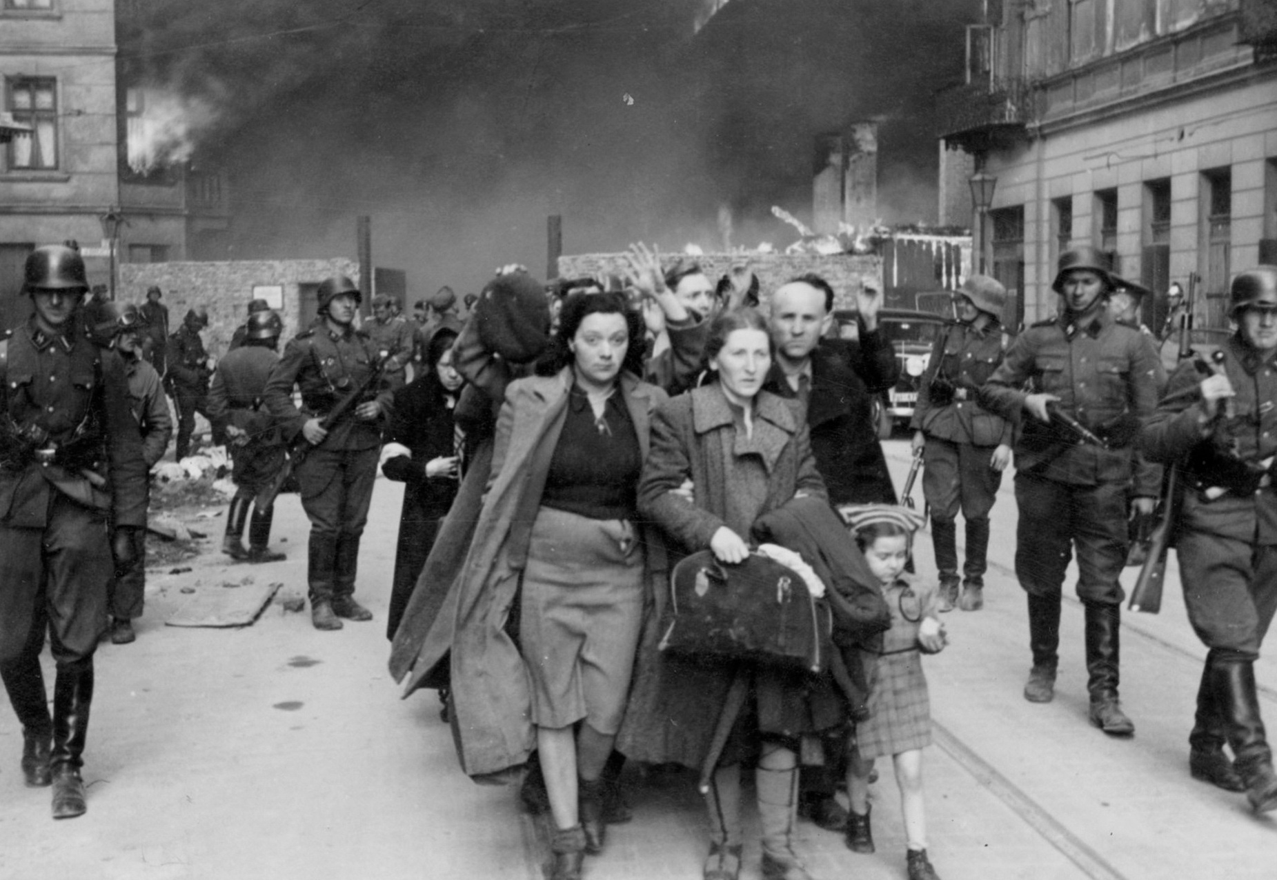 Yehudit Neyer (dark-haired woman), madam Neyer (center), Avraham Neyer (next to child), and the rest of the Neyer family leading a column of Jews being marched out of the Warsaw ghetto gate for deportation, Warsaw, Poland, Apr-May 1943, photo 2 of 2