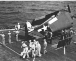 F6F-5 Hellcat rests on the flight deck of USS Bataan as Marine and Navy Honor Guards prepare for a burial at sea off Okinawa, April 18 1945