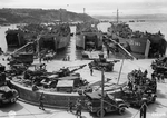 US LSTs 284, 380, 382, and 499 loading men, vehicles, and supplies for the upcoming Normandy Invasion in Brixham Harbor, Devon, England, Jun 1 1944. Note wings and fuselage of an Aeronca L-3 Grasshopper observation aircraft on a CCKW truck.