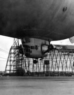 View of the control car of US Navy blimp K-11, Airship Patrol Squadron ZP-11, attempting to land during a storm at NAS South Weymouth, Massachusetts, United States, Sep 27, 1942. Note Hangar One under construction.
