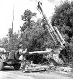US Army patrol examining a German 88 mm FlaK anti-aircraft gun with its barrel splayed by the retreating Germans near Montebourg, France, June 1944