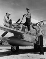 Armorers load belts of .50 caliber ammunition into a P-51D Mustang of the 45th Fighter Squadron, Saipan, Mariana Islands, before flying to Iwo Jima, Mar 1945.