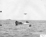 TBF Avenger from Escort Carrier USS Guadalcanal overflying the captured German Type IXC submarine U-505 as a salvage crew assembles on the U-Boat’s bow. A US whale boat and an escort stand by, 7 Jun 1944.