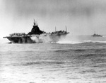 USS Intrepid smoking and listing after being struck by a Japanese special attack aircraft off Okinawa, 16 Apr 1945. Note the volume of water from the fire fighting efforts pouring out of the hangar deck.