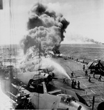 Firefighters of Belleau Wood fighting flames caused by a special attack aircraft, in the Philippine Islands, 30 Oct 1944; note TBM Avenger aircraft on flight deck and Franklin burning in distance. Photo 2 of 2