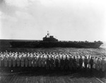 Officers and sailors of USS Saratoga man the rails for HMS Illustrious passing close aboard as the British Eastern Fleet bids farewell to the American carrier, Indian Ocean northwest of Australia, 18 May 1944.