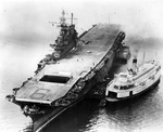 USS Enterprise at anchor in Puget Sound, Washington, US, 7 Jun 1945 still with no forward elevator that was blown off the ship three weeks earlier. Note damage to deck planks and Seattle ferry ‘City of Sacramento’