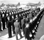 Newly arrived aviation cadets at the Naval Air Station at Corpus Christi, Texas, United States submitting to haircut inspection, circa 1942. Note OS2U Kingfisher aircraft.