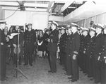 Captain Warren K Berner, left, reading his orders to take command of the training carrier USS Sable at her commissioning ceremony at the American Shipbuilding Company in Buffalo, New York, 8 May 1943.