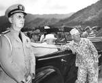 While touring Oahu, US Territory of Hawaii, President Franklin Roosevelt (seated in car) listened to Col William Saffarans (in jungle suit) at the Army’s Jungle Training Unit at Kahana Bay, 28 July 1944.