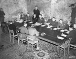 Officers gather around a table at Eisenhower’s headquarters to sign the instruments of the German surrender, Reims, France, 7 May 1945. Photo 2 of 2