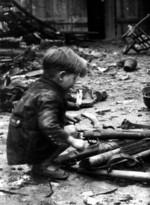 German child playing with abandoned weapons, Berlin, Germany, 1945