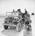 Members of the British 11th Royal Horse Artillery, First Armoured Division, pose with their Canadian Chevrolet-built CMP 4x4 truck, messenger motorcycle, and canine mascot, Tunisia, 22 Apr 1943.