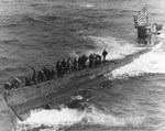Boarding party from USS Pillsbury working to secure a tow line to U-505’s bow in the western Atlantic, 4 Jun 1944. Note the large United States flag flying from the submarine’s periscope.