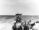 Boarding party working on the captured U-505’s bow in the western Atlantic as the carrier USS Guadalcanal approaches to take the submarine in tow, 4 Jun 1944.