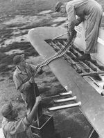 Armorers loading belts of .50 caliber ammunition into the four ammo trays in one wingtip of a P-47 thunderbolt, date and location unknown.