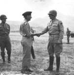 British General Bernard Montgomery and American Lt General George Patton shake hands at a Tunisian airstrip prior to the Sicily Invasion, mid 1943. I Armored Corps Deputy Commander Geoffrey Keyes is at left.