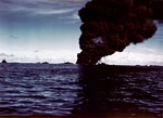 A column of smoke 500 feet wide rising from the capsized and burning fleet oiler USS Mississinewa after being struck by the first Japanese Kaiten deployed, Ulithi Atoll, 30 Nov 1944.