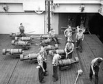 Aircraft elevator aboard the escort carrier USS Santee loaded with aerial depth charges on bomb dollies on their way up to the flight deck for loading onto TBF Avengers, Nov 1943 in the Atlantic.