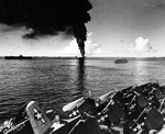 Smoke rising from the overturned and burning fleet oiler USS Mississinewa in Ulithi Lagoon, 20 Nov 1944 as seen from the carrier Lexington (Essex-class). Ticonderoga is at left and hospital ship Solace is at right.