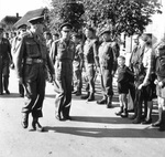 As General Neil Ritchie and King George VI of the United Kingdom complete their review of an Army honor guard, they themselves are reviewed by a Dutch family near Nijmegen, Netherlands, 13 Oct 1944.
