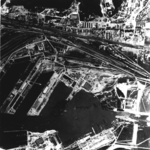 Aerial view of Gotenhafen (Gdynia), occupied Poland, Jun 1942, photo 2 of 2; photo taken by a British RAF aircraft; note battlecruiser Gneisenau (white arrow) and carrier Graf Zeppelin (bottom)