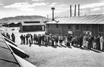 Internees lining up for the noon meal at the Manzanar Relocation Center for deported Japanese-Americans, Inyo County, California, United States, 1943.