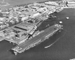 USS Bennington alongside Ford Island at Berth F-2 in Pearl Harbor, Hawaii, 23 Jan 1946. Note her freshly painted peacetime white deck markings and camouflage paint on some of the Ford Island buildings.