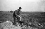 Western war correspondent inspecting abandoned Japanese Type 91 or Type 95 gas masks and other chemical warfare equipment in the field, Changde, Hunan Province, China, 25 Dec 1943