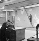 Sergeant Holland speaking with Section Officer Bewkey while Corporal Tomkinson places markers on a wall map and Aircraftwoman Tarrant recorded data on a chalkboard, on set of film Coastal Command, Pinewood Studios, Iver Heath, England, United Kingdom, 1942