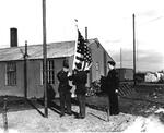 Two United States Army soldiers and one RAF corporal raising the colors at RAF Thurleigh, Bedfordshire, England, circa 1944.