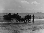 Men of 4th Regiment of 6th Division of US Marine Corps landing via a LCVP from USS Waukesha at Yokosuka, Japan, 30 Aug 1945; note 75mm pack howitzer, battleship Nagato (background), and Yokosuka Naval Arsenal (right edge of photograph)