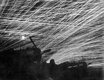 Anti-aircraft tracers in the night sky above Yontan Airfield, Okinawa, Japan, 28 Apr 1945; note US Marine Corps Corsair fighters in foreground