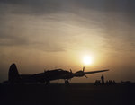 B-17 Flying Fortress bomber at rest, silhouetted by the setting sun, Langley Field, Virginia, United States, Jul 1942; note B-18 Bolo and two A-20 Havoc aircraft in background