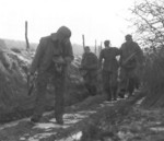 Troops of Company H, 3rd Battalion, 504th Infantry Regiment, US 82nd Airborne Division escorting a captured German SS soldier, Bra, Belgium, 25 Dec 1944