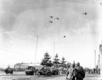 Troops of US 101st Airborne Division watching C-47 Skytrain aircraft delivering supplies to their unit, Bastogne, Belgium, 26 Dec 1944