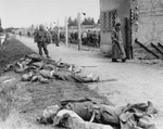 An American soldier standing beside the bodies of SS personnel shot by US troops during the liberation of Dachau Concentration Camp, Germany, 29-30 Apr 1945