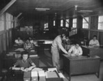 Virginia Shilby (foreground left), John Tucker (center), and other workers at the Housing Department office of Jerome War Relocation Center, Arkansas, United States, 17 Nov 1942