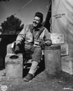 American Red Cross assistant field director Herbert M. Sifford grinding coffee in a camp near Tebessa, Tunisia before heading out to meet soldiers, 19 Feb 1943