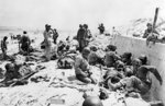 Americans of the 4th Infantry Division being tended by US Medical Corpsmen by a sea wall at Utah Red Beach, Normandy, France, morning of 6 Jun 1944