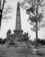 African-American US Marines and sailors resting at the base of a Japanese war memorial, Okinawa, Japan, 12 Apr 1945. On steps: Snowden, Martin. On monument: Walton, Ellenberg, Brown, Brawner.
