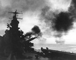 Cruiser USS Phoenix firing her 6-inch guns during the invasion of Cape Gloucester, New Britain, Bismarck Archipelago, circa 24-26 Dec 1943; note photo was taken from fantail, looking forward